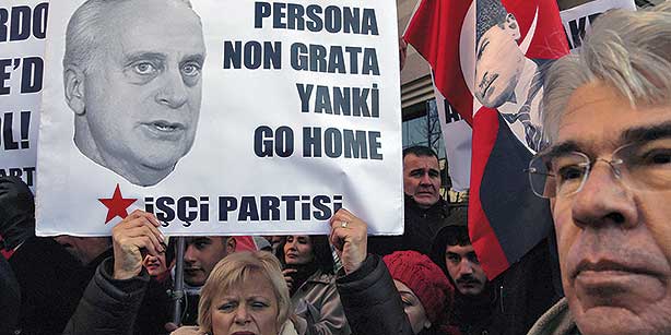 A Turkish protester holds a sign with a photo of US Ambassador Francis Ricciardone during a protest held by leftist Workers’ Party outside the US Embassy in Ankara on Dec. 23, 2013. (Photo: AP)