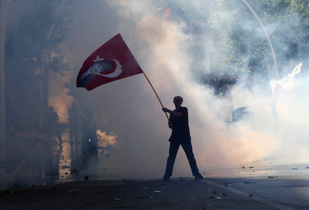 Tear gas surrounds a protestor holding a Turkish flag with a portrait of the founder of modern Turkey, Mustafa Kemal Ataturk, as he takes part in protests against the Turkish Prime Minister and his ruling Justice and Development Party (AKP) in Ankara on June 1, 2013. (Adem Altan/AFP/Getty Images)