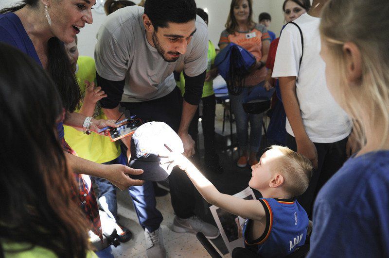 Kyle Phillips / The Transcript. 
Oklahoma City Thunder’s Enes Kanter gives Henry Hale a hat earlier this year during his visit at the J.D. McCarty Center. Kanter, an outspoken critic of the current Turkish government, has been facing increasing pressure from Turkey to stop talking. His passport has been canceled, a warrant for his arrest has been issued, and his father was arrested this morning.