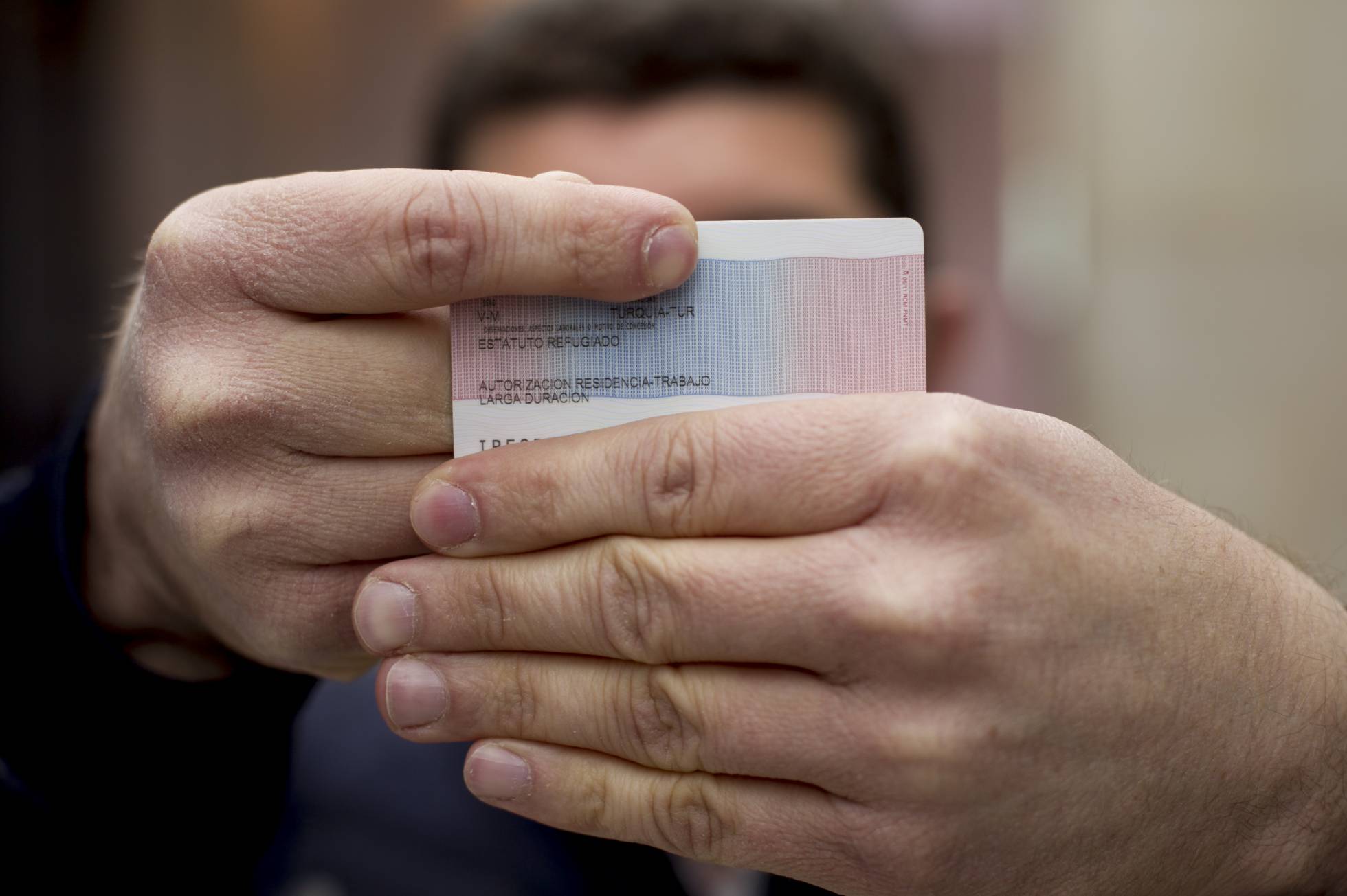 The first Turkish citizen granted political asylum in Spain shows his refugee ID card. SANTI BURGOS EL PAIS